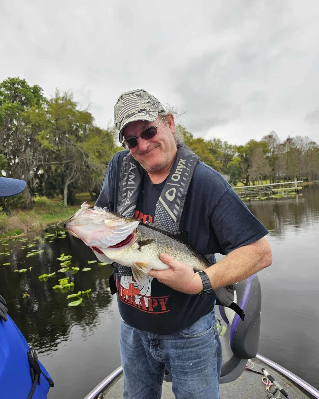 Ken holding a largemouth bass on his boat
