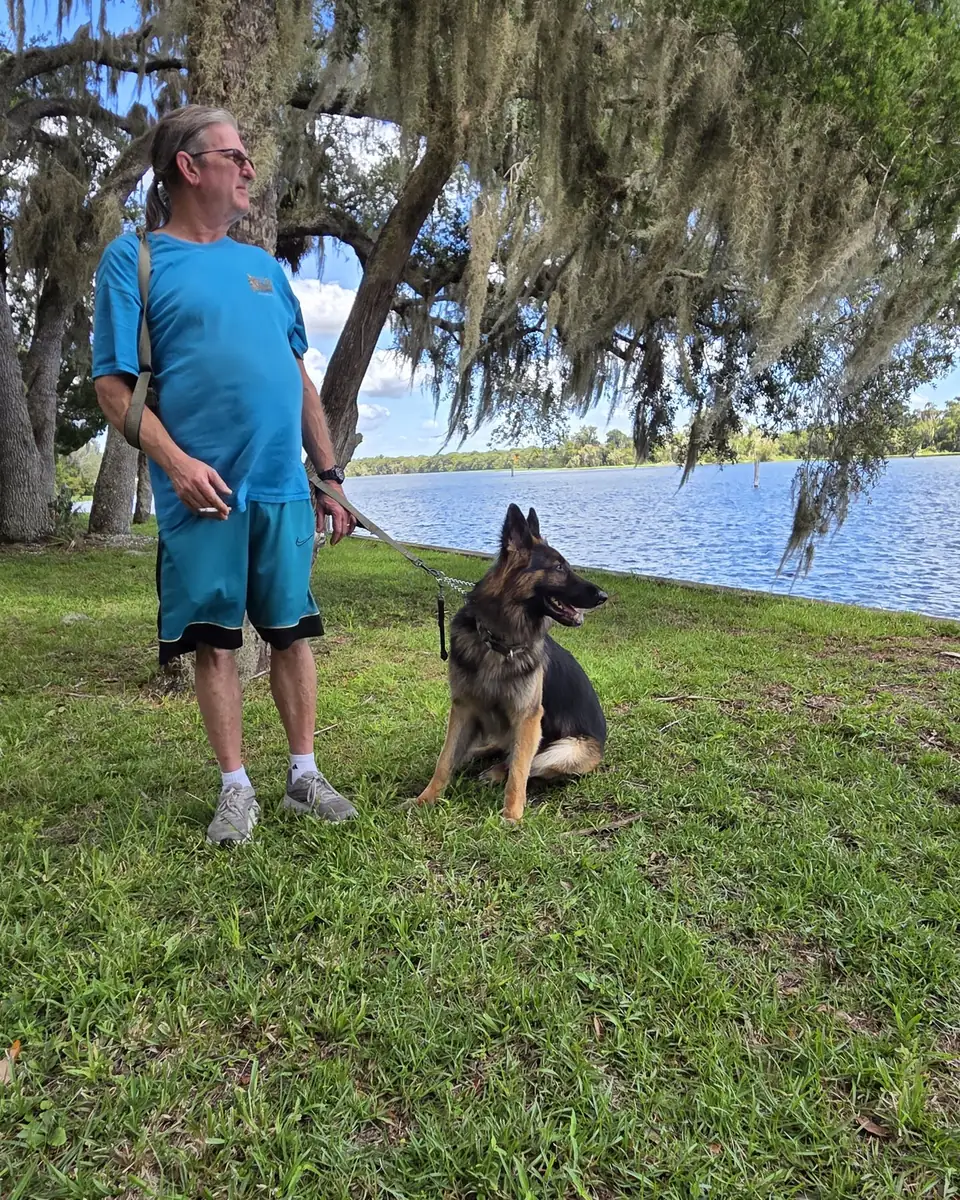 Ken Knorr standing by the lake with his German Shepherd, Gunny