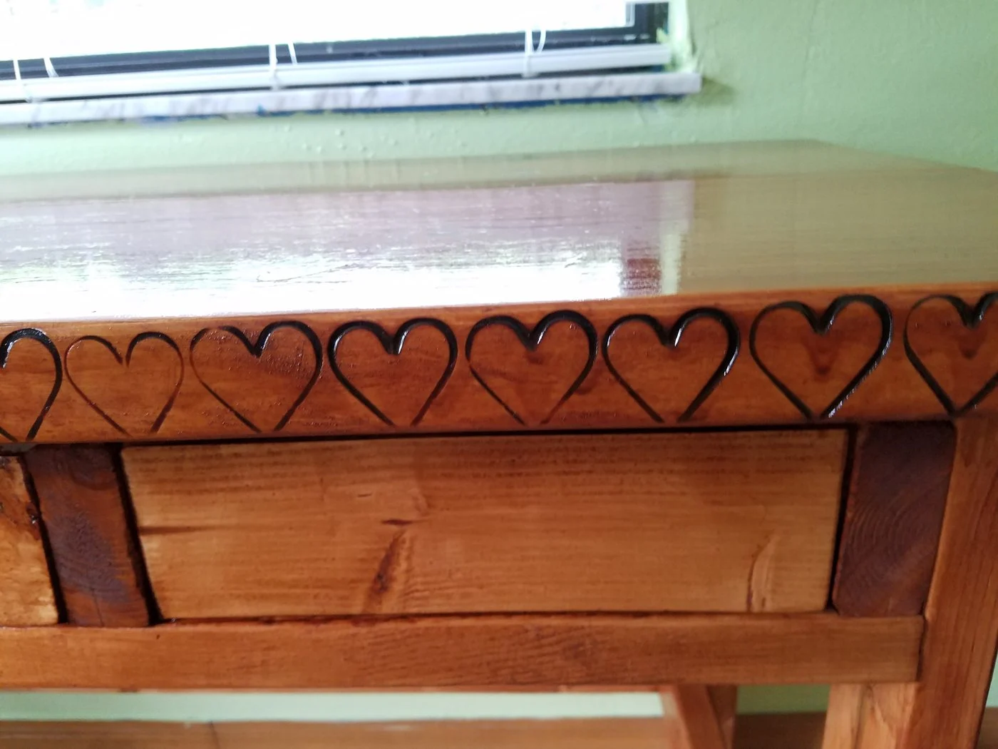 Hand-carved row of hearts on a wooden table apron